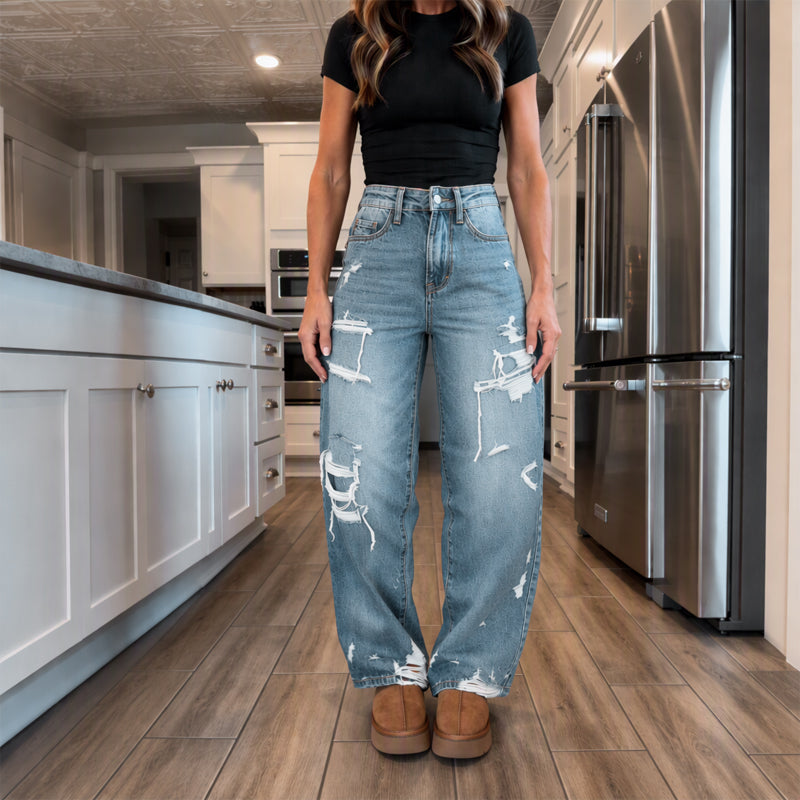 Elegant kvinner i slitne denim-bukser med vide ben