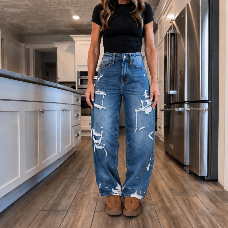 Elegant kvinner i slitne denim-bukser med vide ben