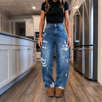 Elegant kvinner i slitne denim-bukser med vide ben