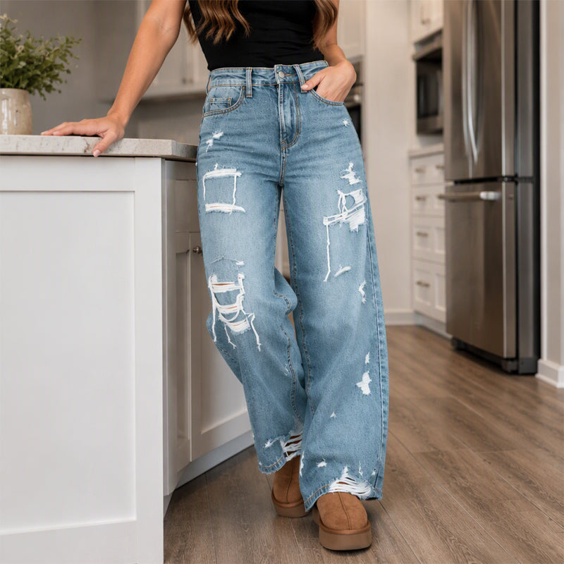 Elegant kvinner i slitne denim-bukser med vide ben