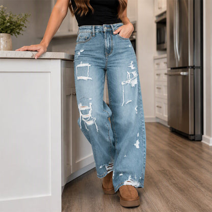 Elegant kvinner i slitne denim-bukser med vide ben
